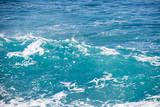 Turquoise blue sea texture with waves and foam.