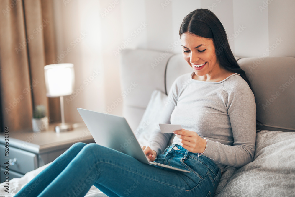 Girl sitting on the bed and using laptop for online shopping. Girl sitting on the bed and using laptop for online shopping.