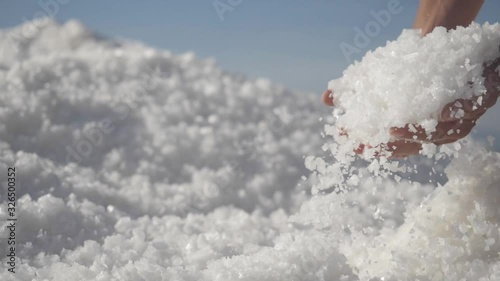 Hands holding salt crystals. Male hand holding natural salt crystals on the background of a salt lake. White natural salt