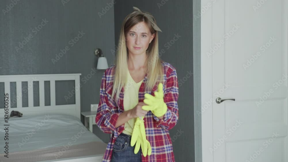 Young housewife puts on yellow gloves Young housewife puts on yellow gloves
