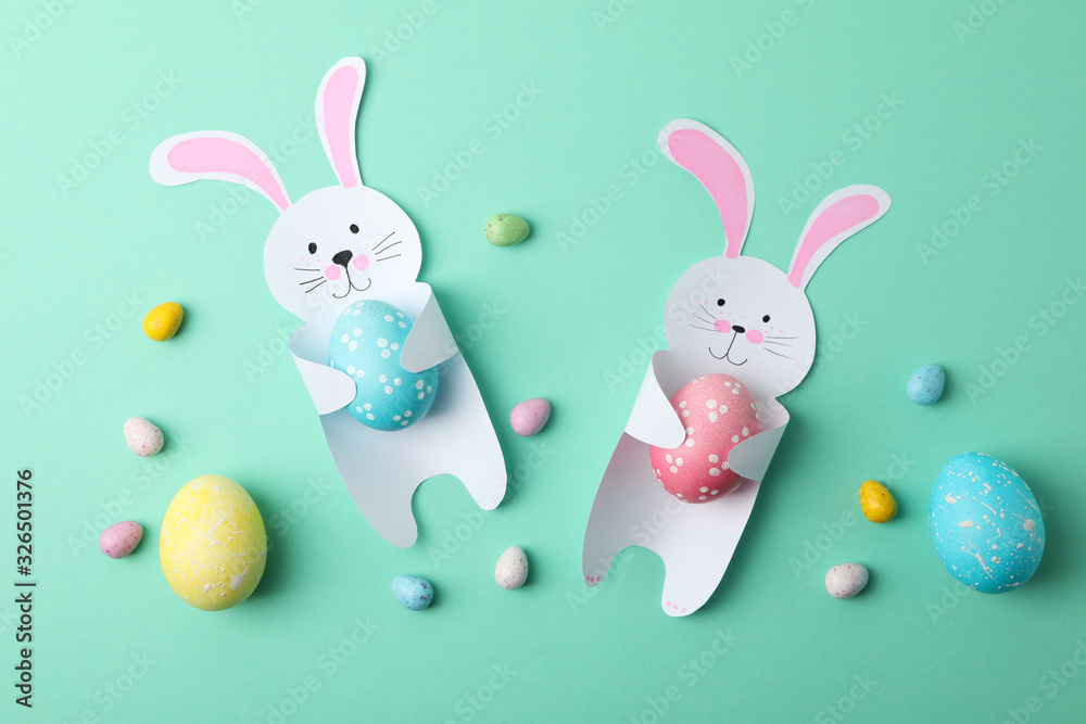 Obraz premium Decorative bunnies and Easter eggs on mint background, top view