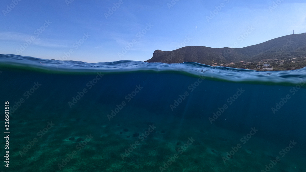 Beautiful underwater split above and below photo of rocky seascape with deep blue sky in tropical exotic island destination Beautiful underwater split above and below photo of rocky seascape with deep blue sky in tropical exotic island destination