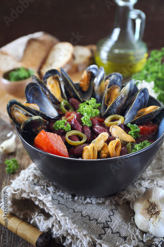  Southern cuisine of Italy. Cantabria food. Soup with mussels, tomatoes and red beans, parsley dressing
