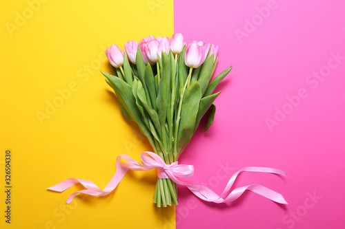 Boquet of pink tulips on the yellow and pink background.Easter,spring flower concept,copy space.Mothers or Womans day.