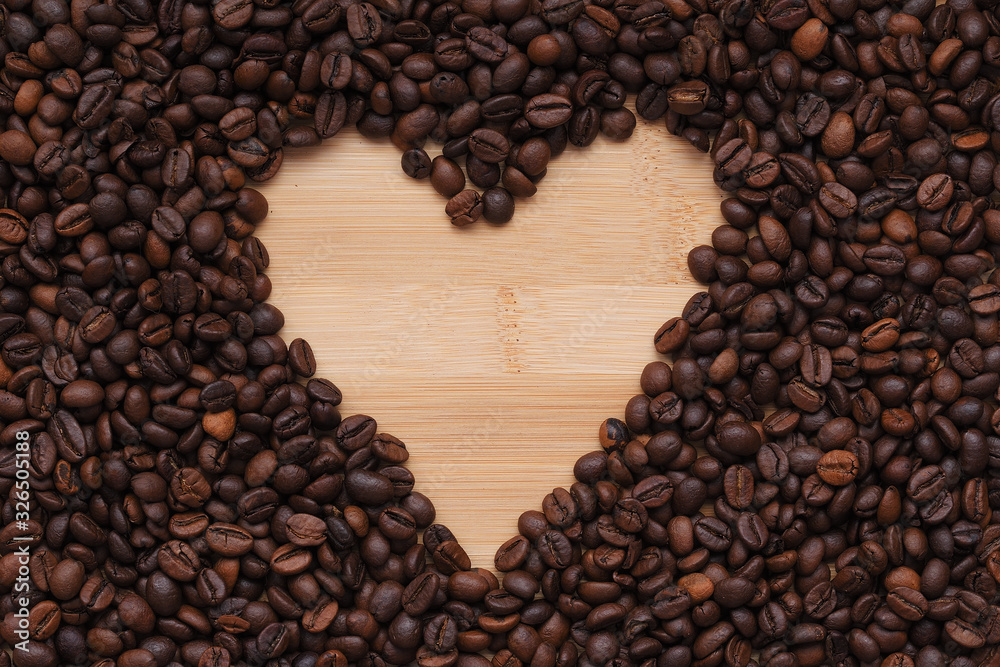 coffee beans laid out in the shape of a heart on a wooden surface. the view from the top coffee beans laid out in the shape of a heart on a wooden surface. the view from the top