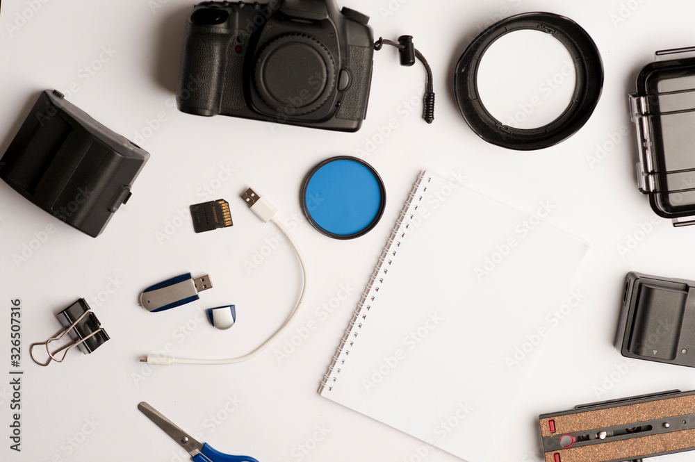 Flat assembly composition with photographic production equipment, with writing book, and accessories, on plain white background, top view Flat assembly composition with photographic production equipment, with writing book, and accessories, on plain white background, top view