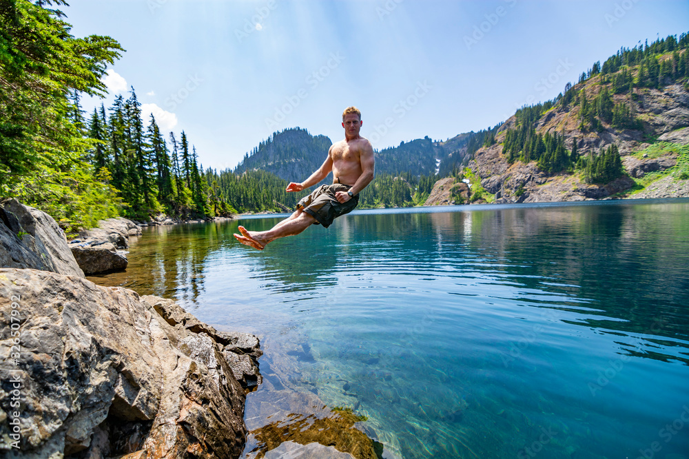 Male hiker jumping into an alpine lake in Washington State.