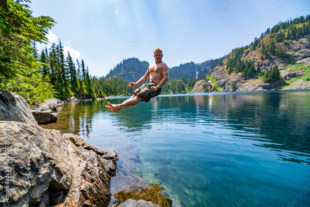 Male hiker jumping into an alpine lake in Washington State. Male hiker jumping into an alpine lake in Washington State.
