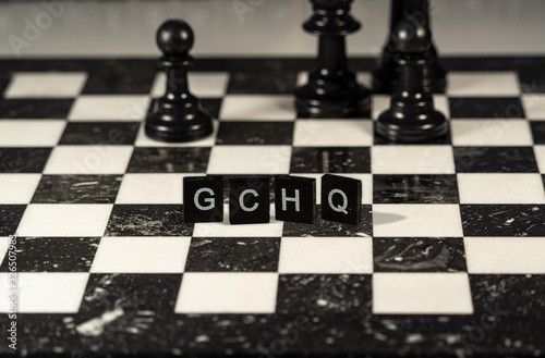 Gchq the word or concept represented by black and white letter tiles on a marble chessboard with chess pieces photo