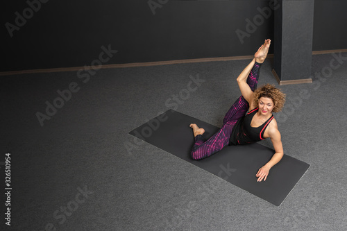 Sporty fit beautiful woman with blond hair in sportswear working out, doing Anantasana, Side-Reclining Leg Lift pose, Sleeping Vishnu posture, studio full length, top view, grey background, copy space photo