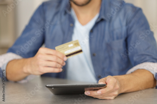 young man using his credit card and tablet