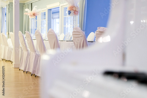 White lacquered piano against the background of a banquet hall. Decor and interior for the holiday