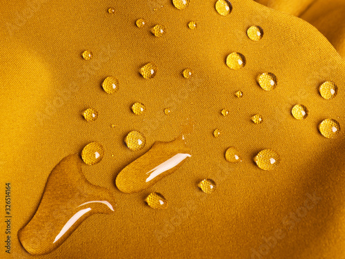 Yellow waterproof fabric with raindrops close up