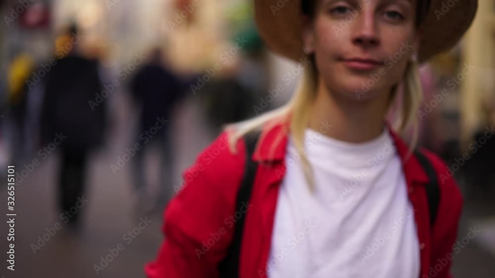 Portrait of blonde authentic caucasian woman traveler standing on street looking at camera, slow motion effect of female tourist in red t-shirt looking at camera and holding mobile phone in hand Portrait of blonde authentic caucasian woman traveler standing on street looking at camera, slow motion effect of female tourist in red t-shirt looking at camera and holding mobile phone in hand