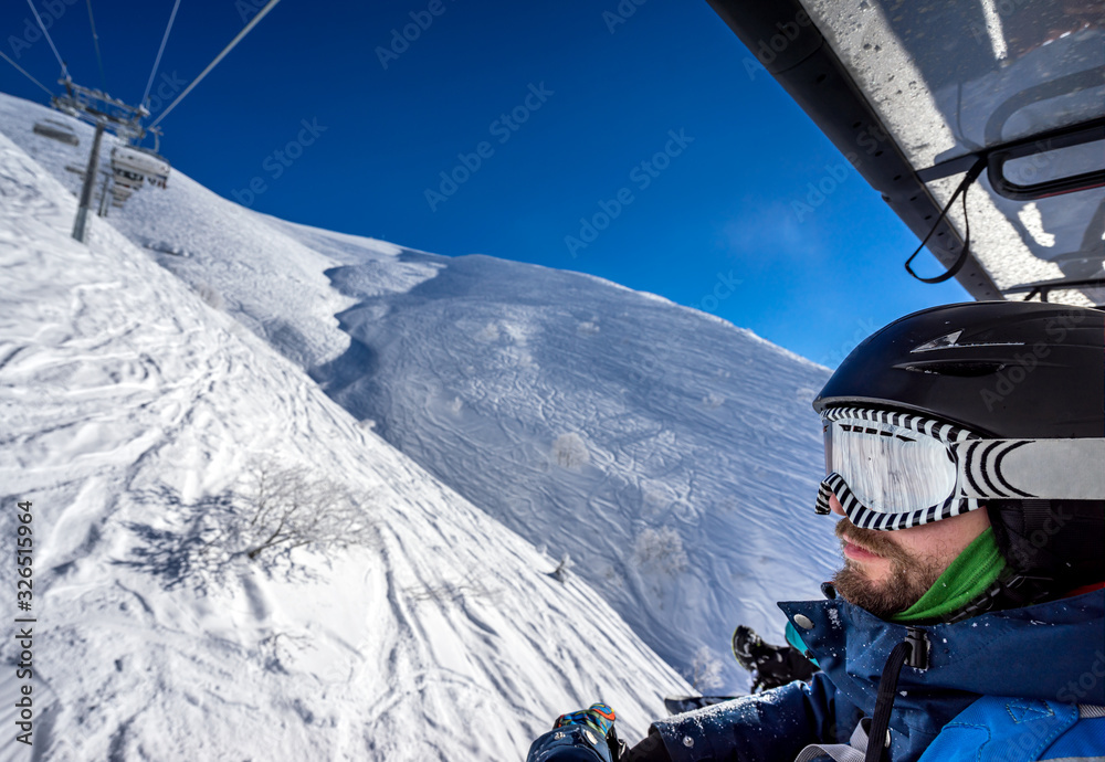 Snowboarder freerider in motion on the cable car rises to the top of the mountain in the winter resort of Rosa Khutor