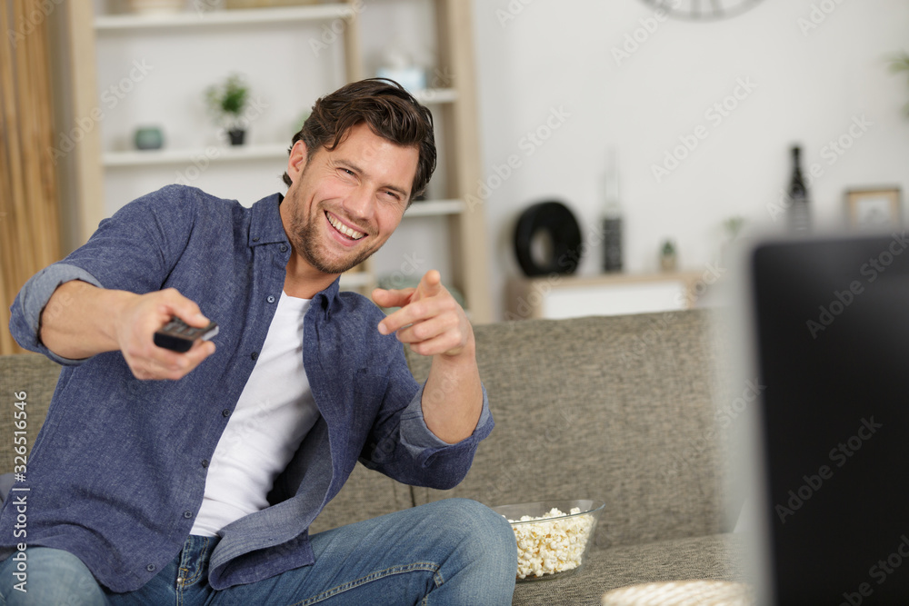 man holding a remote pointing and smiling