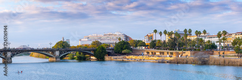 Panoramic view of the waterfront of the Guadalquivir River in Seville, Andalusia, Spain. On a warm winter evening, people relax and stroll along the waterfront. photo