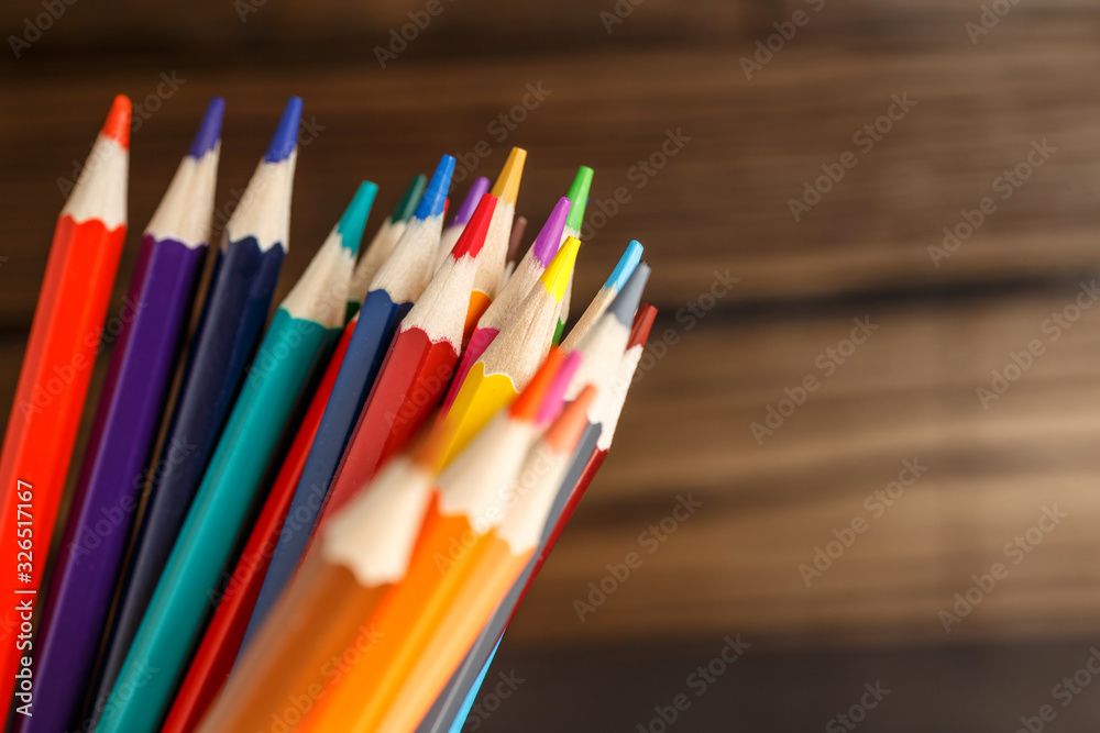 Fototapeta premium Pens and pencils in metal holder in front of wall background