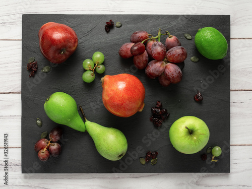 fruits background green and red color composition on dark stone slake plate and white wood table. Summer abstract creative trendy fresh health concept. Flat lay top view