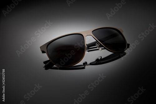Sunglasses on a black gradient, matte background, shallow depth of field. The concept is stylish and beautiful.