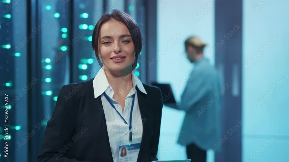 Smart woman engineer typing on tablet diagnosing rack server cabinet. Smiling cheerful female specialist enjoying coworking process at modern data center. Smart woman engineer typing on tablet diagnosing rack server cabinet. Smiling cheerful female specialist enjoying coworking process at modern data center.