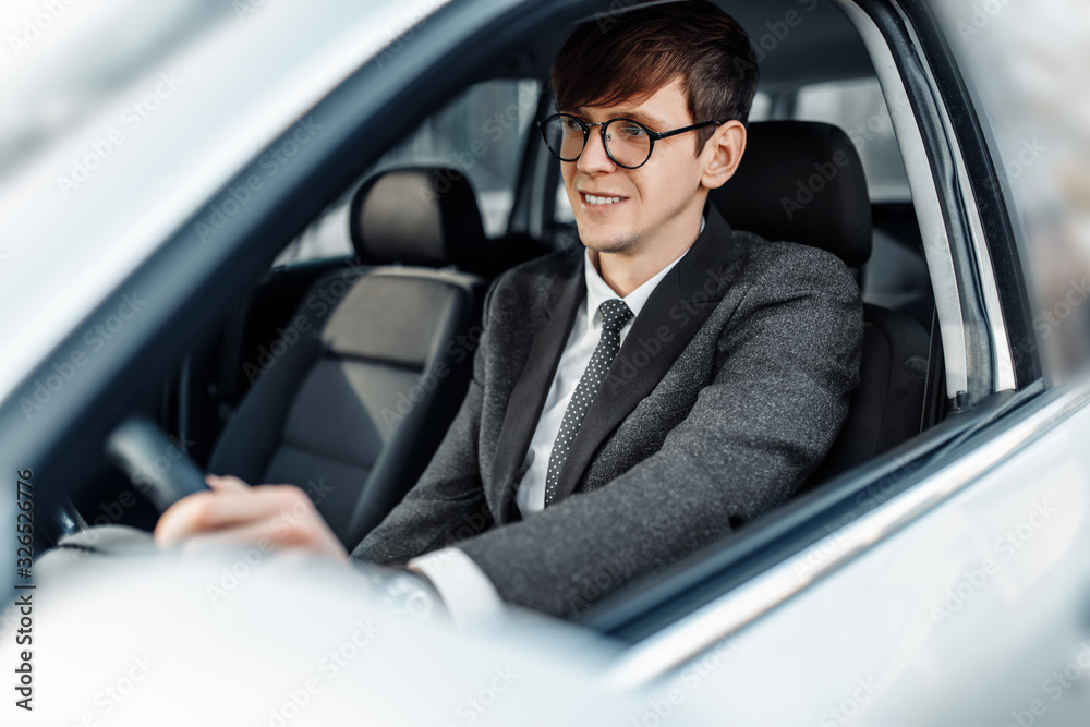 Attractive elegant young businessman driving a car