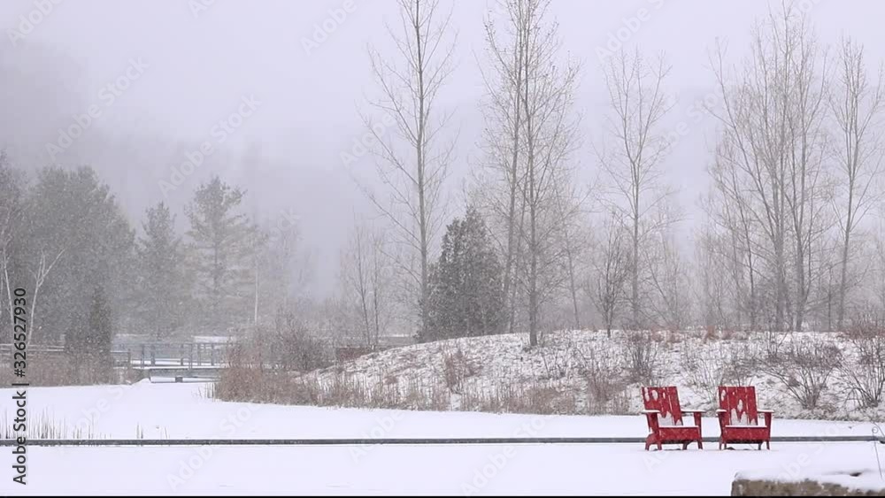 Winter snow falling upon ponds and forest with red Muskoka chairs in Don Valley Brick Works Park, Toronto, Ontario, Canada Winter snow falling upon ponds and forest with red Muskoka chairs in Don Valley Brick Works Park, Toronto, Ontario, Canada