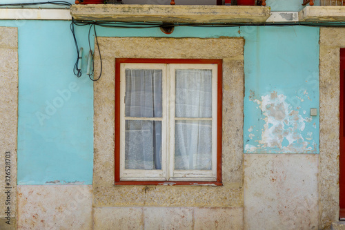 Square window on a pale blue, wheathered facade in Lisbon, Portugal. photo