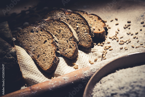 dark sliced ​​bread with wheat and flour on the table. Sliced ​​rye bread on a close-up on the table and scattered grains of wheat around Brown bread and grains look beautiful. Put on a wooden table.
