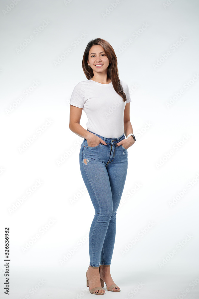 Smiling woman in white T-shirt standing with the hands in the pockets, white background Smiling woman in white T-shirt standing with the hands in the pockets, white background