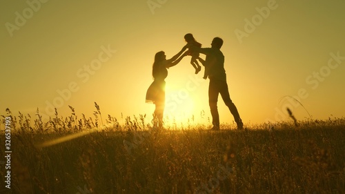 concept of happy childhood. child  dad and mom play in the meadow in the sun. mother  father and little daughter walking in a field in the sun. Happy young family. concept of a happy family.
