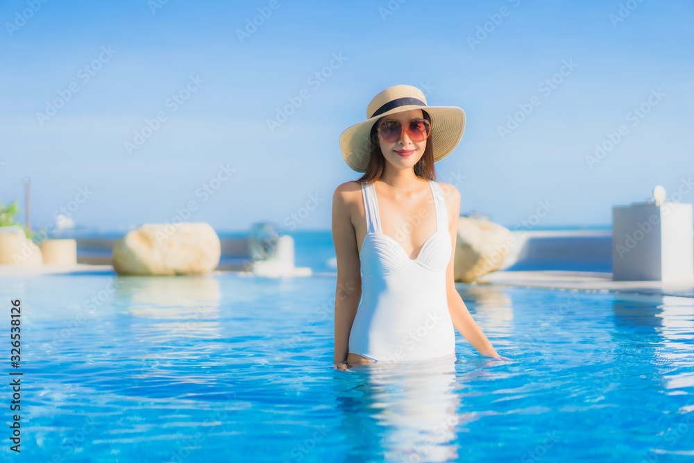 Portrait beautiful young asian woman happy smile relax around outdoor swimming pool in hotel resort