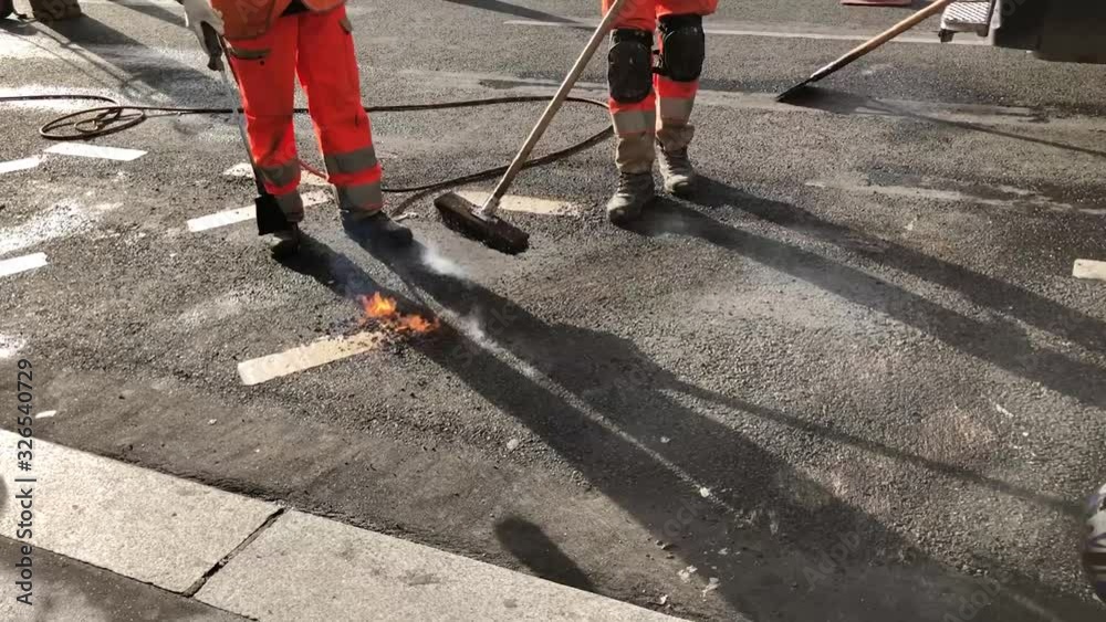 Effacement de marquage au sol et réparation de nid de poules grâce  à un chalumeau et balai par des travailleurs