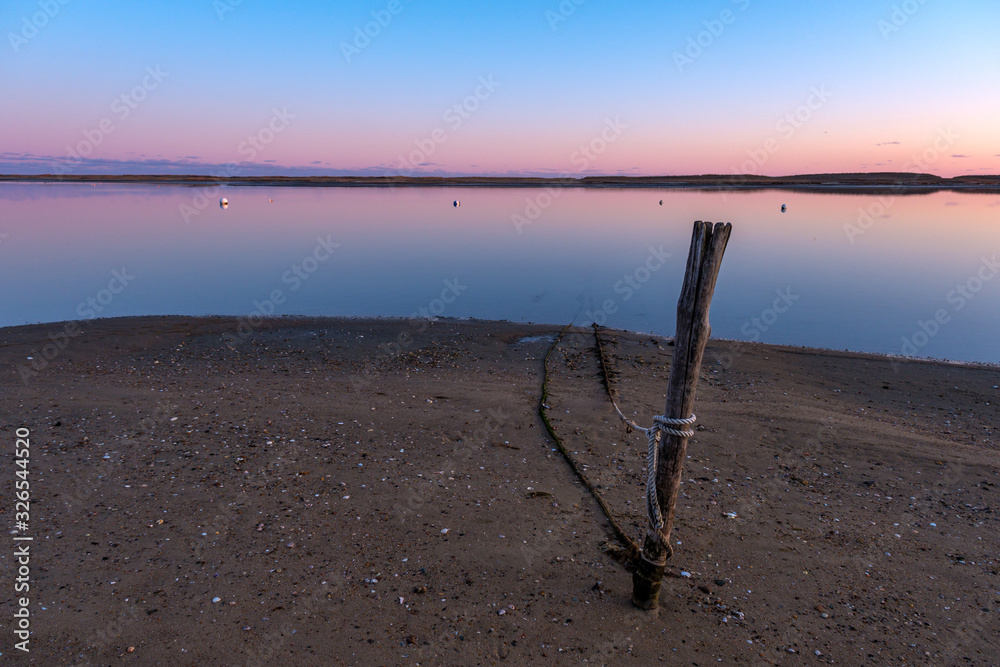 Sunset on an empty harbor, with a mooring line tied to a stake in the beach sand Sunset on an empty harbor, with a mooring line tied to a stake in the beach sand