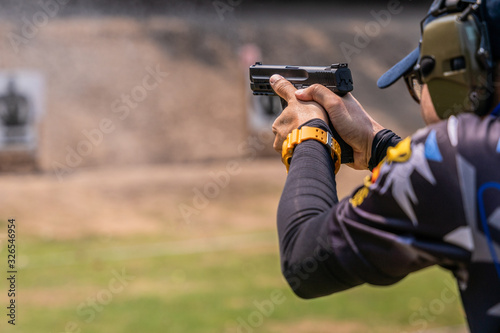 selective focus of man holding and fire handgun in gun shooting competition photo
