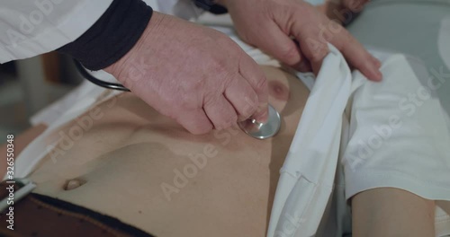 Close view of doctor listens to sick boy's breath with phonendoscope in hospital photo