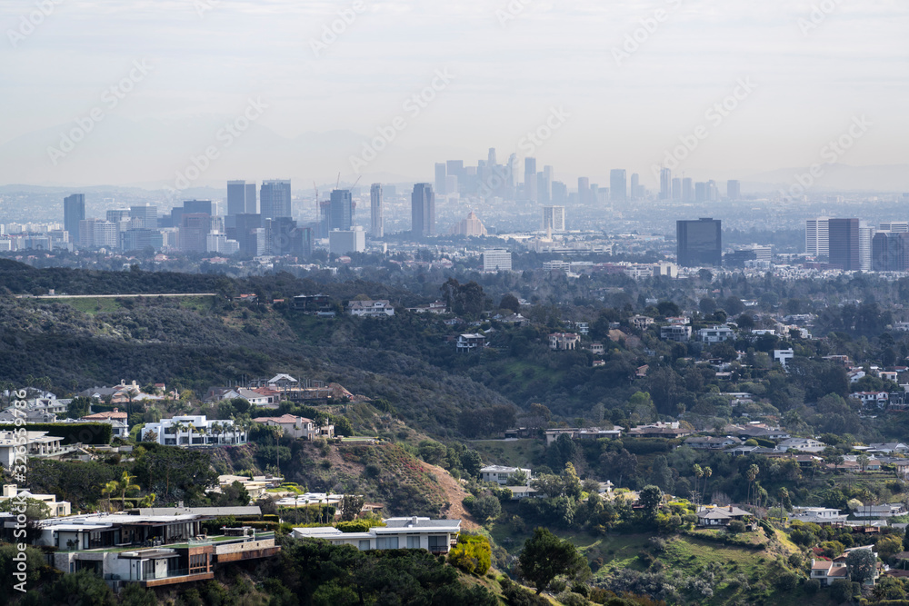 Obraz premium Canyon homes with hazy smoggy cityscape view of Century City and Downtown Los Angeles skylines. 