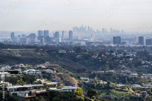 Canyon homes with hazy smoggy cityscape view of Century City and Downtown Los Angeles skylines.  