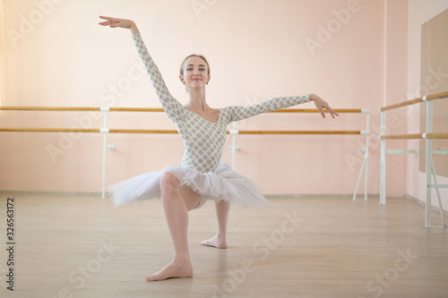 A very flexible ballerina in a tutu stands in a plie in a class with ballet machines. Hypermobility of joints and connective tissue dysplasia. photo