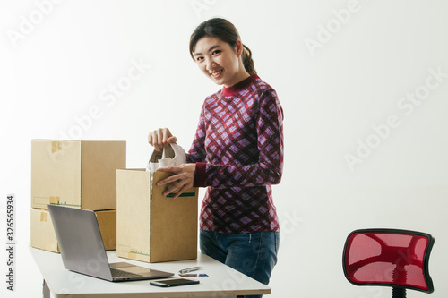 Portrait of young Asian casual woman working small business online packing shoe to cardboard box