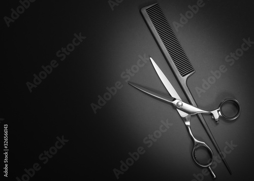 Scissors and comb. Beauty salon equipment. Shears for haircut on black background. Copy space, flat lay view