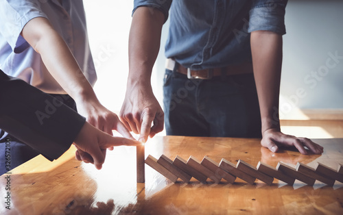 Business teamwork risk control concept, Business team protect wooden block fall to planning and strategy in risk to business Alternative and prevent. Investment Insurance Business.