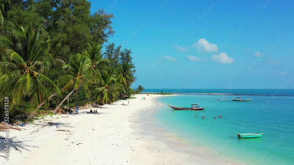Palm tree shade over white sandy beach surrounded by blue turquoise sea water under the beautiful sky. Thailand Palm tree shade over white sandy beach surrounded by blue turquoise sea water under the beautiful sky. Thailand