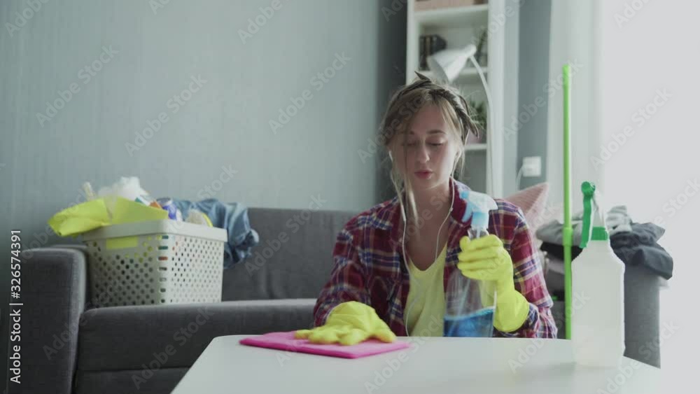 Attractive young woman funny housekeeper is having fun during dusting table. Attractive young woman funny housekeeper is having fun during dusting table.