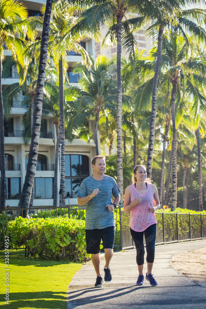 Middle aged couple jogging together at a tropical beach resort. Staying fit and enjoying time together on vacation