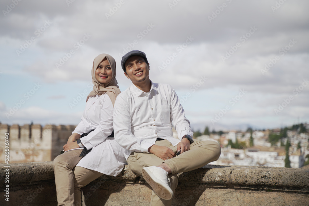 Stylish Asean Muslim couples enjoy the view in the corner of the famous traditional Islamic Alhambra building in Spain during the day