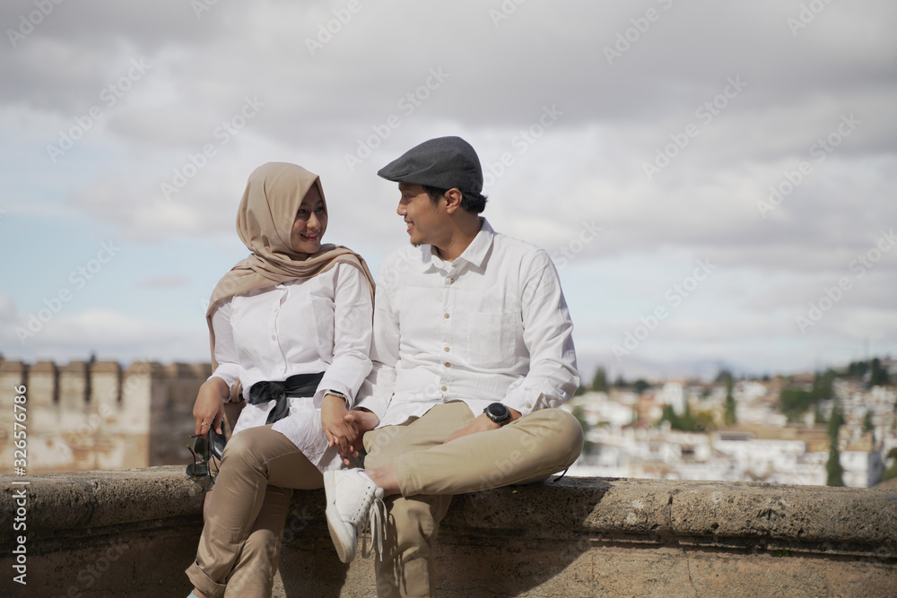 Stylish Asean Muslim couples enjoy the view in the corner of the famous traditional Islamic Alhambra building in Spain during the day Stylish Asean Muslim couples enjoy the view in the corner of the famous traditional Islamic Alhambra building in Spain during the day
