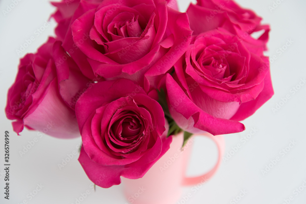 Bouquet of pink roses on a light background. A bouquet of flowers stands in a pink mug. Pink vase. Bouquet of pink roses on a light background. A bouquet of flowers stands in a pink mug. Pink vase.