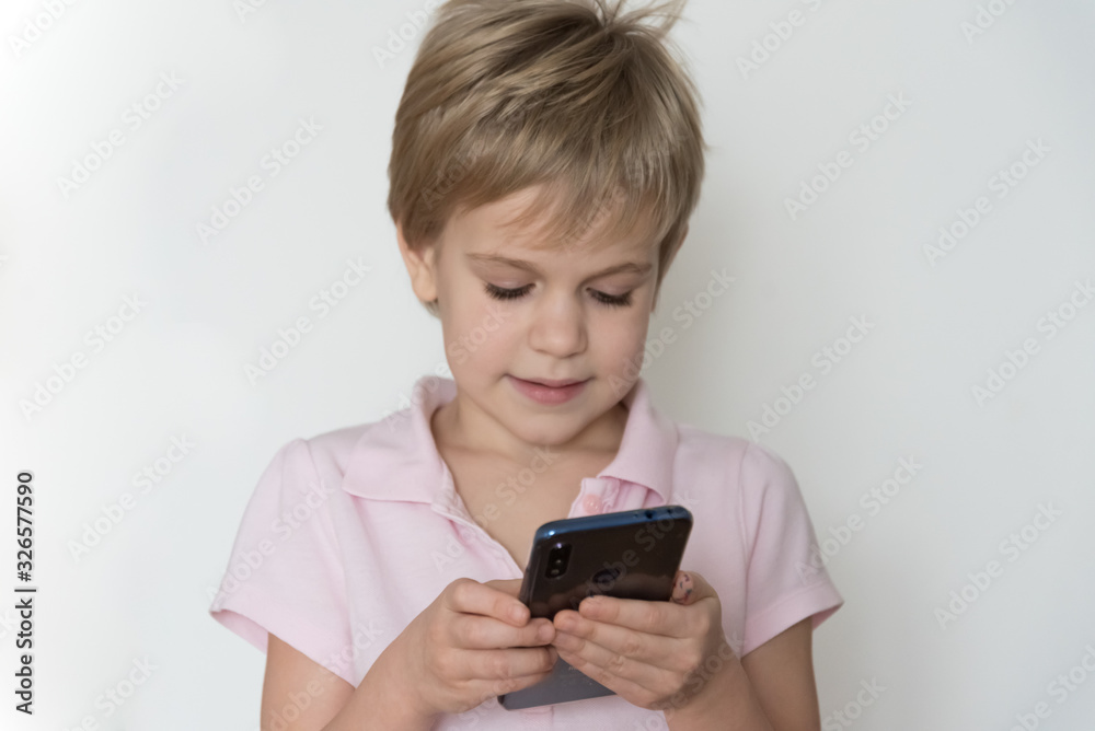 A cute child is laughing loudly, holding a cell phone in his hand. A cute child is laughing loudly, holding a cell phone in his hand.