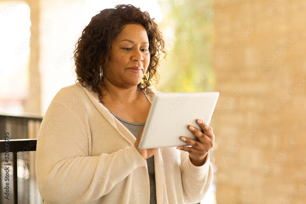 Fototapeta premium Smiling African American woman working on a tablet.